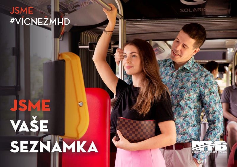 Plakát brněnského dopravního podniku s heslem „Jsme vaše seznamka“, na kterém se k ženě držící madlo zezadu naklání usměvavý muž